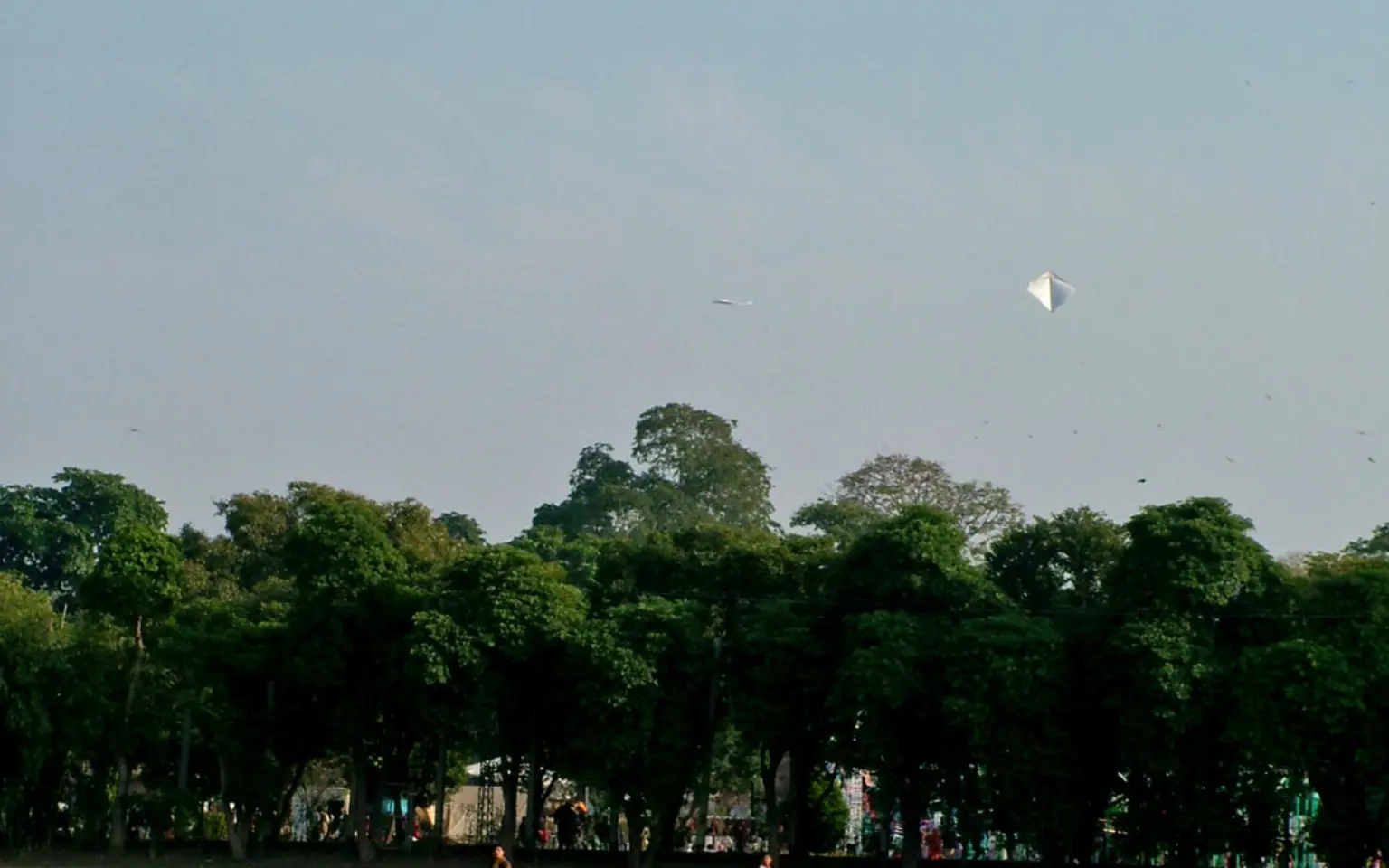 Children flying kites over open ground in Lahore