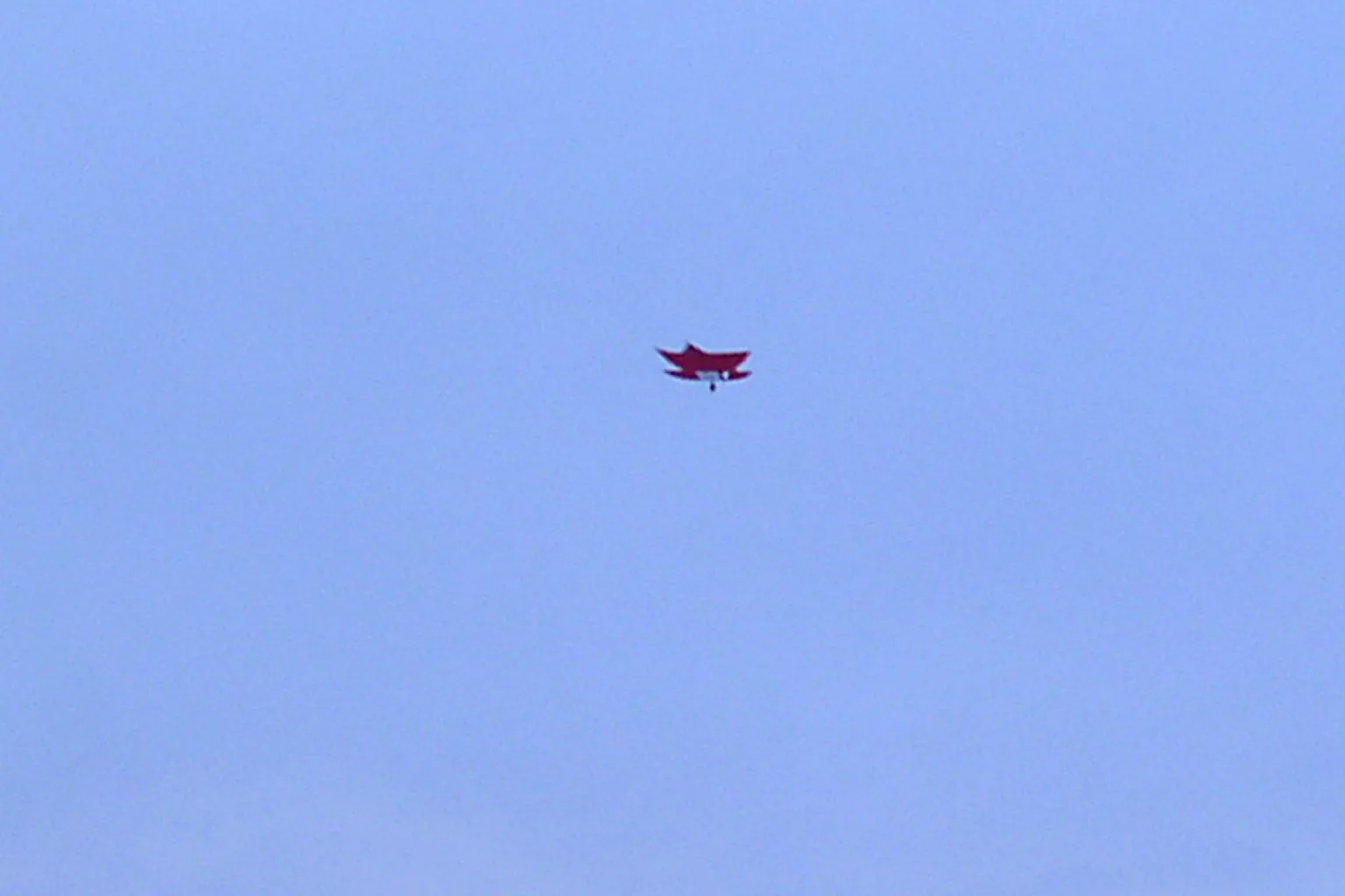 A single paper kite high in a clear blue sky over Lahore